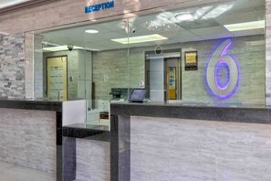 A reception area with a glass partition, a reception desk, and a number '6' sign. - 1 King Bed | Non-Smoking, Kitchen (Artesia)