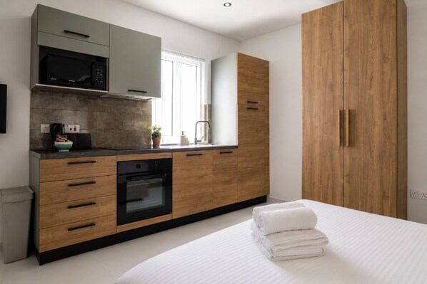 Une cuisine moderne équipée d’un four à micro-ondes, d’un four traditionnel et de meubles de rangement en bois.
