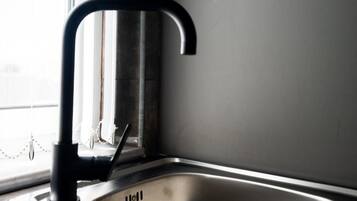 A stainless steel kitchen sink with a black faucet, positioned next to a window.