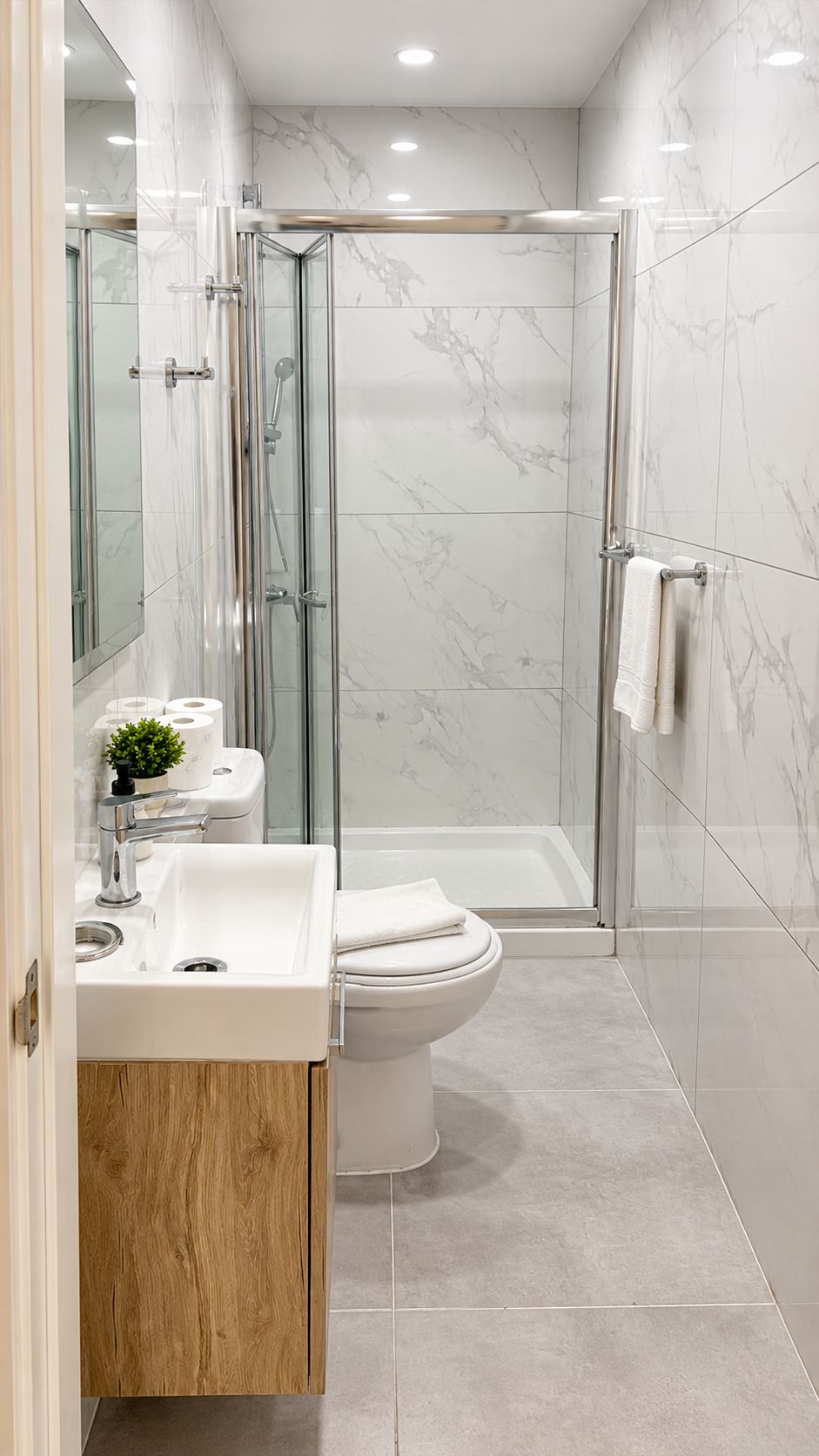 A modern bathroom with a glass-enclosed shower, a white sink, and a toilet.