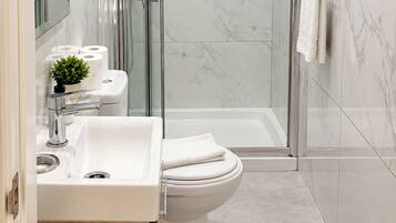 A modern bathroom with a glass-enclosed shower, a white sink, and a toilet.