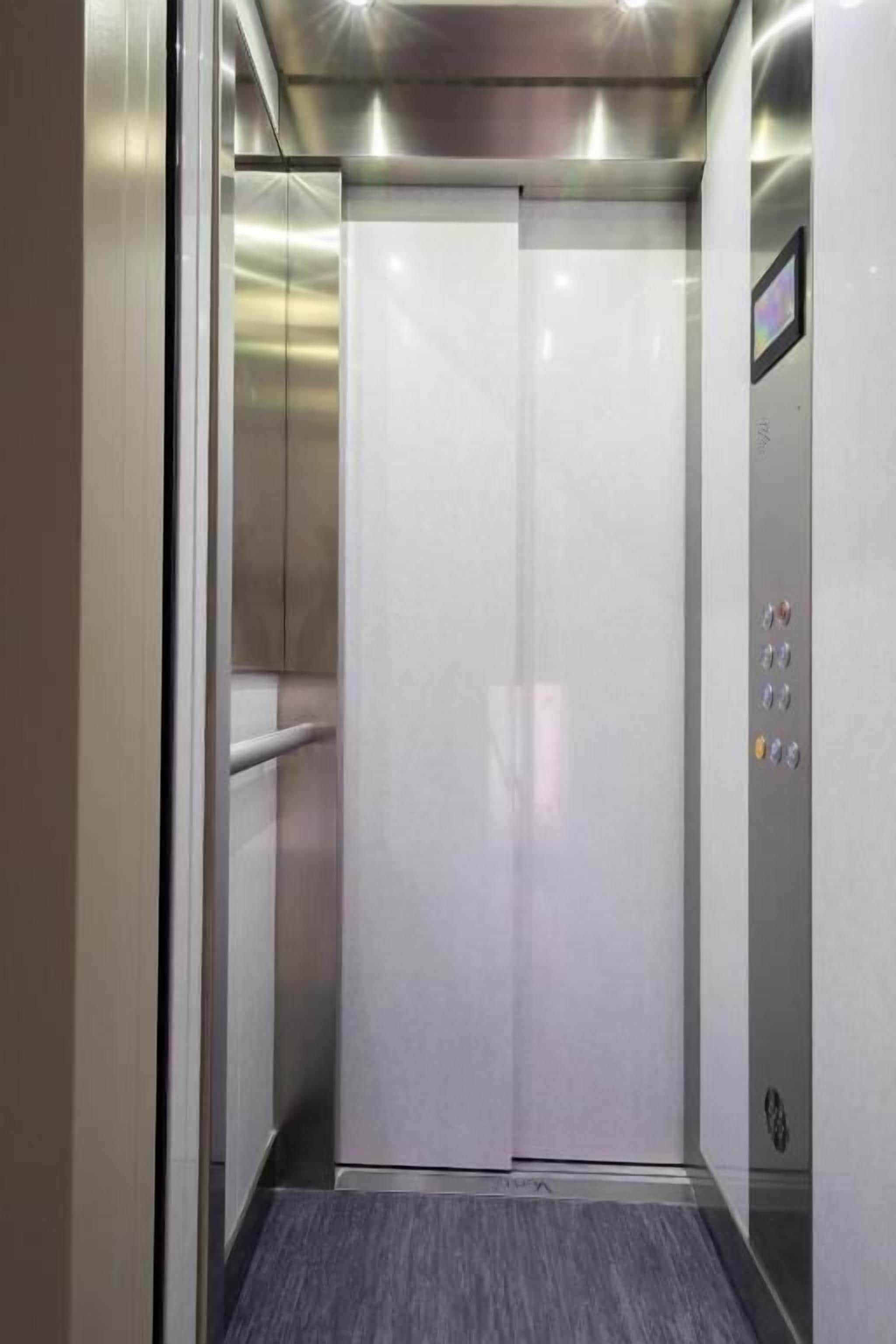An elevator with a metallic interior and a control panel on the right side.