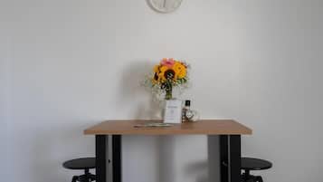 A small table with a clock, a welcome sign, and a vase with flowers.