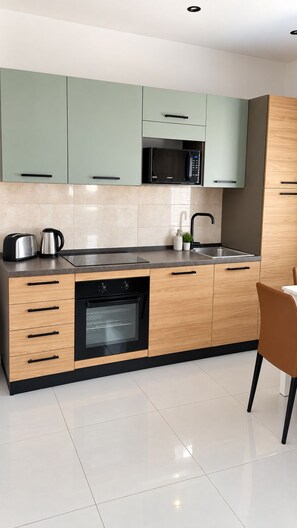 A modern kitchen with a built-in microwave, oven, and sink. - Marina Studions (Bormla)