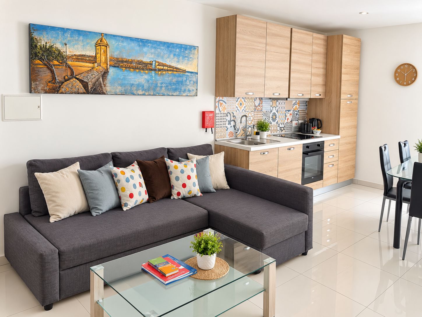 A modern living room with a grey sofa, a glass coffee table, and a painting of a bridge.