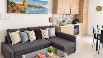 A modern living room with a grey sofa, a glass coffee table, and a painting of a bridge.