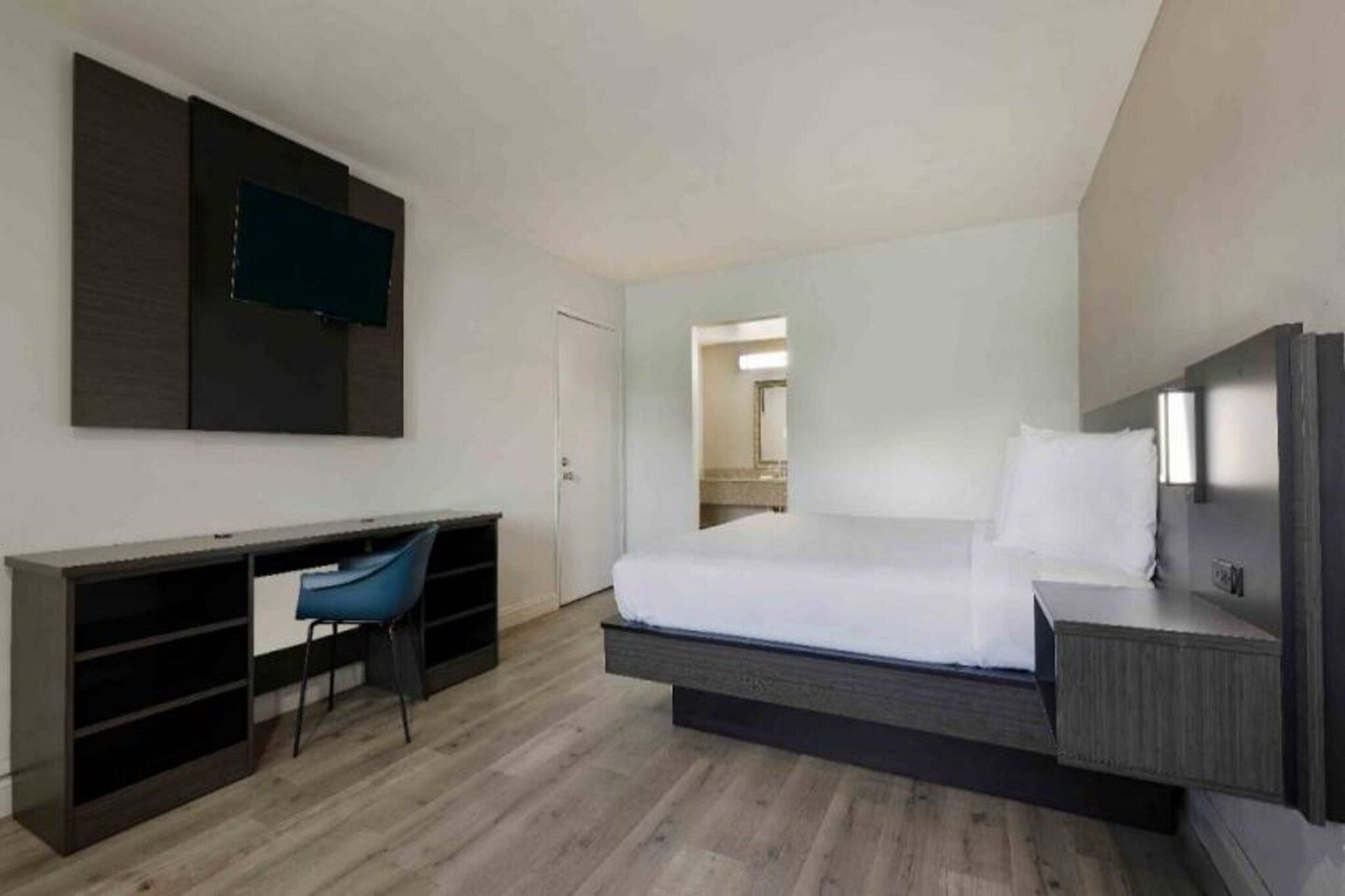 Ein modernes Hotelzimmer mit einem Bett, einem Schreibtisch und einem Stuhl.