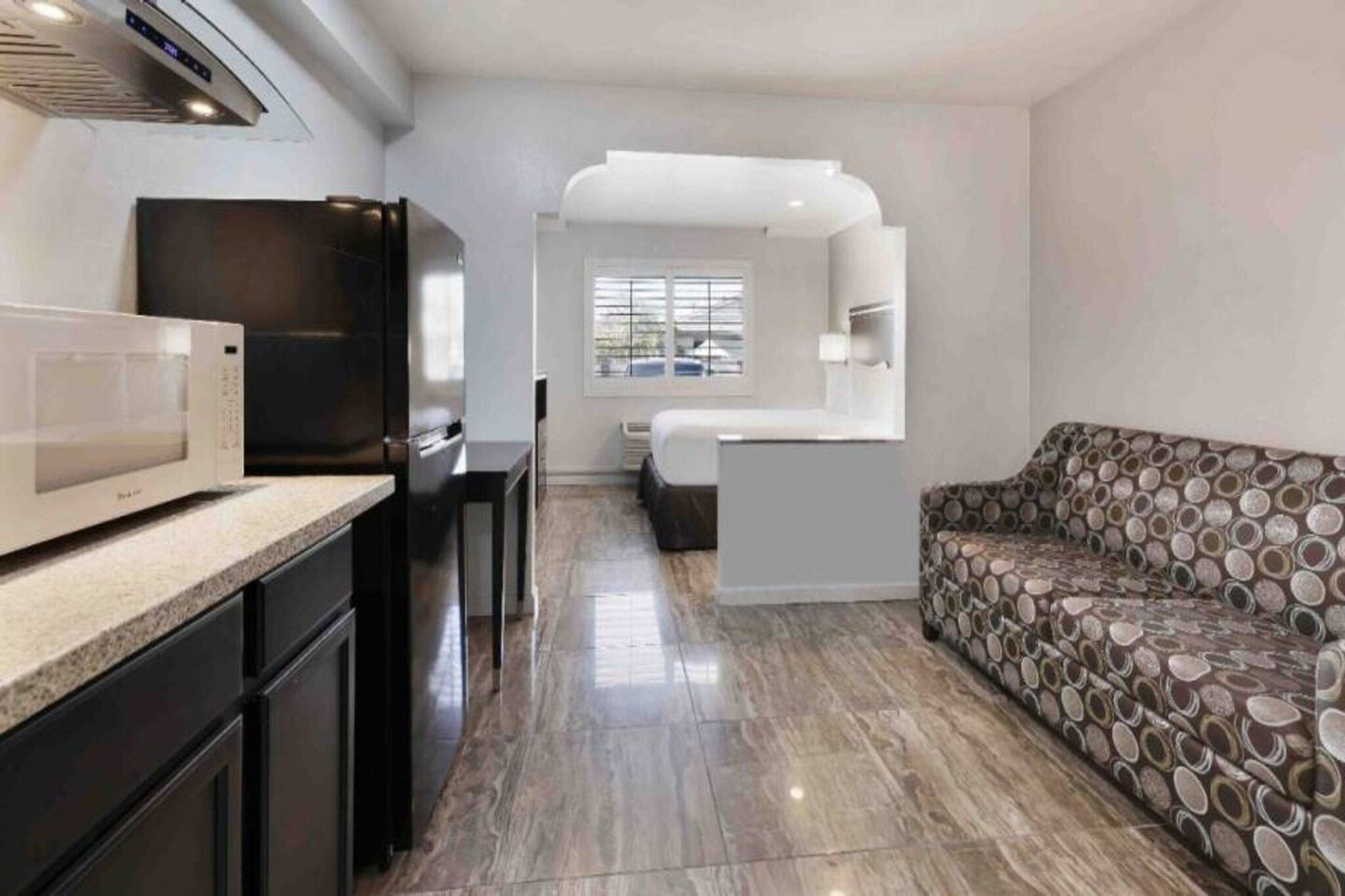 Un espace de vie compact comprenant une kitchenette, un canapé et une fenêtre.