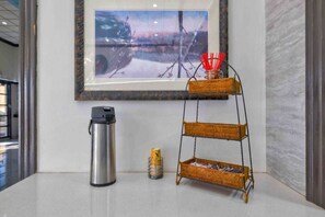 A framed artwork on the wall, a stainless steel thermos, a stack of cans, and a three-tiered wicker shelf with red straws. - 1 Queen Bed | Nsmk, Hot Tub, Micfridge (Artesia)