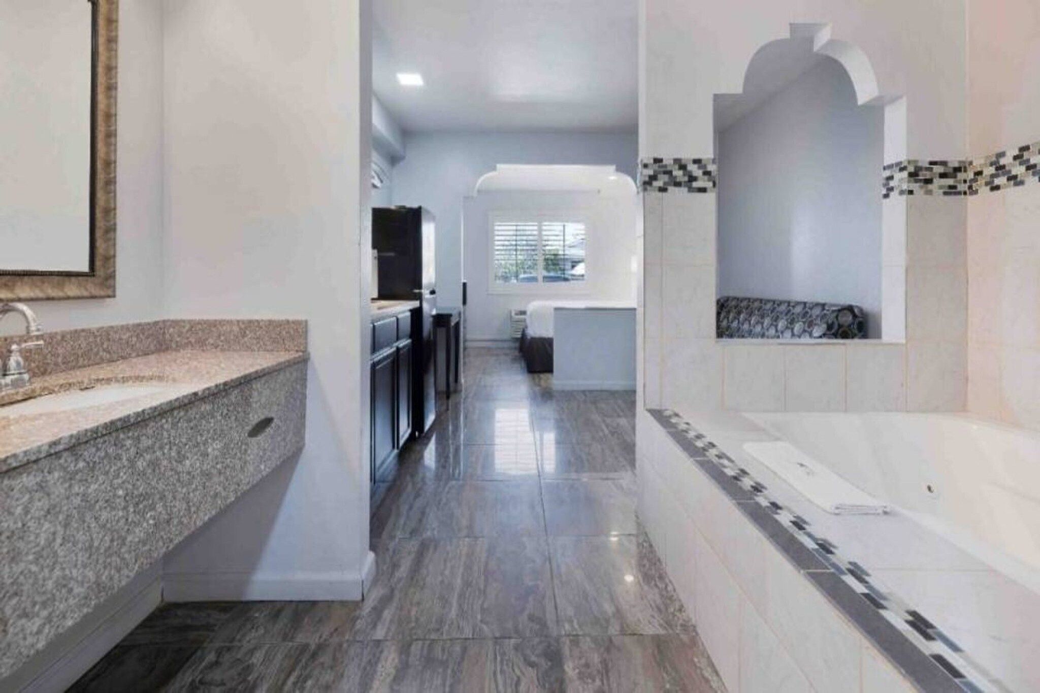 A modern bathroom with a granite countertop, a bathtub, and a shower area.