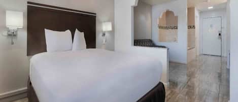 A hotel room with a large bed, a headboard, two wall-mounted lamps, and a marble floor.