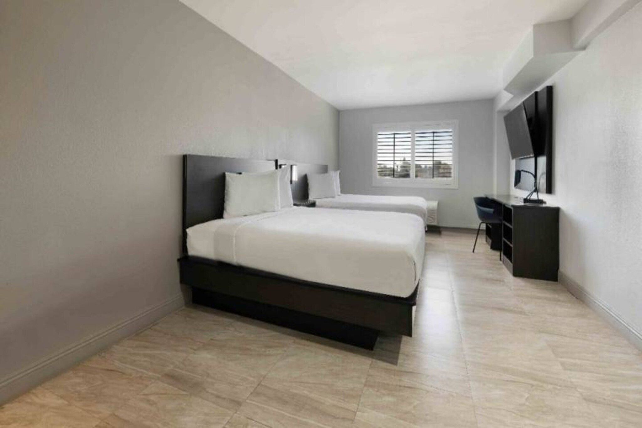 Une chambre d’hôtel moderne avec un grand lit, un bureau et une télévision.