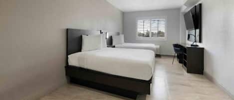 A modern hotel room with a large bed, a desk, and a TV.