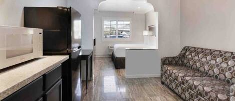 A compact living space with a kitchenette, a sofa, and a window.