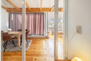 Ein modernes Interieur mit Essbereich, Holzboden und Blick durch eine Glastür.
