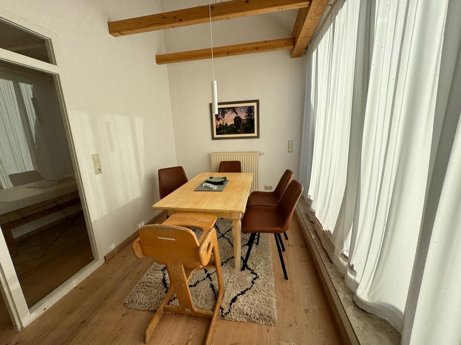 Ein Essbereich mit Holztisch und -stühlen, einem Heizkörper und einem gerahmten Bild an der Wand.