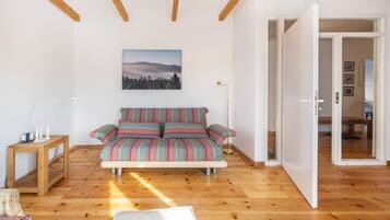 Ein Zimmer mit Holzboden, einer Couch mit gestreiften Kissen, einem Tisch mit Kerzen und einem Bild an der Wand.