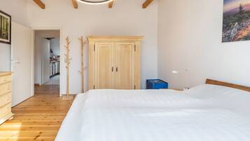 A bedroom with a large bed, wooden flooring, a wardrobe, and a painting on the wall.
