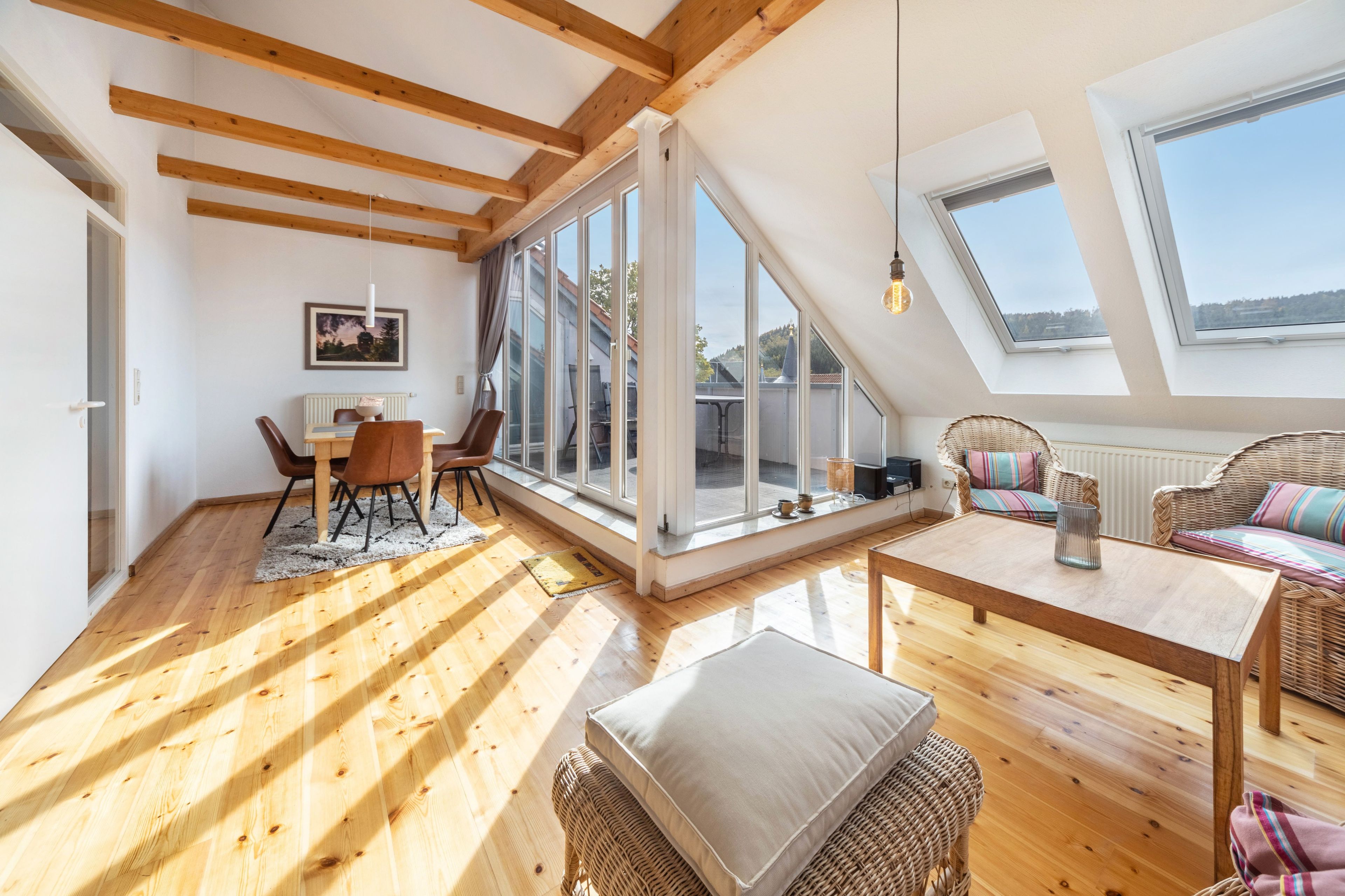 Ein großzügiges Loft mit hohen Decken, großen Fenstern und Holzbalken.