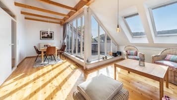 Ein großzügiges Loft mit hohen Decken, großen Fenstern und Holzbalken.