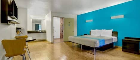 A hotel room with a bed, a desk, and a chair.