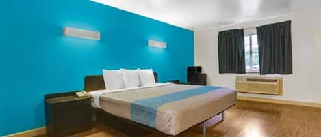 Una habitación de hotel con cama, mesitas de noche, un calefactor y una ventana con cortinas.