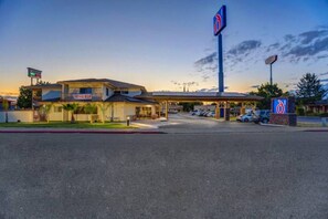 A motel with a gas station, a large sign, and a parking lot.
