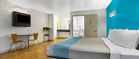 A hotel room with a bed, a desk, a chair, a television, and a bathroom.