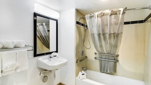 Un bagno con lavandino, specchio, doccia e portasciugamani.