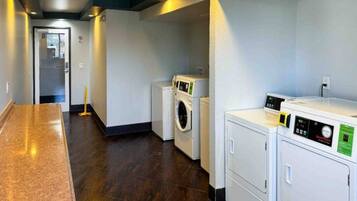 A laundry room with a washing machine, dryer, and stacked laundry baskets.