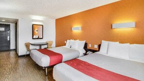 Una camera d'albergo con due letti, un tavolino e uno specchio.