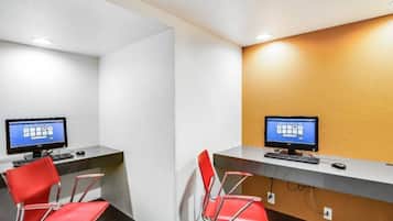 Dos estaciones de trabajo con sillas rojas, paredes blancas y una pared de acento de madera.