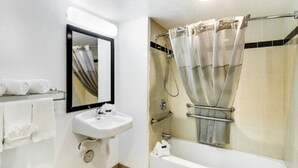 Casa de banho com lavatório, espelho, chuveiro e porta-toalhas.