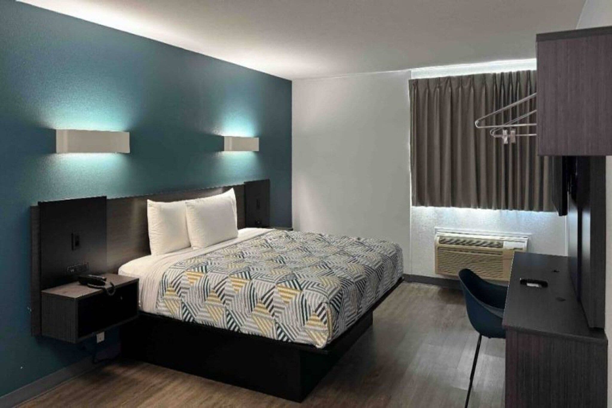 A modern bedroom with a bed, bedside tables, a desk, and a window with curtains.