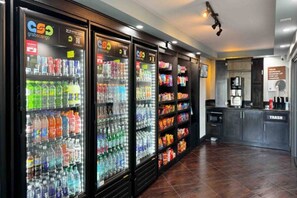 Una fila de dispensadores de bebidas y estantes con aperitivos en un entorno comercial.