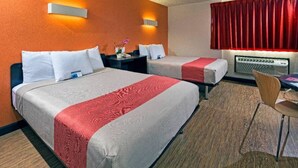 Quarto de hotel com duas camas, uma escrivaninha e uma cadeira.