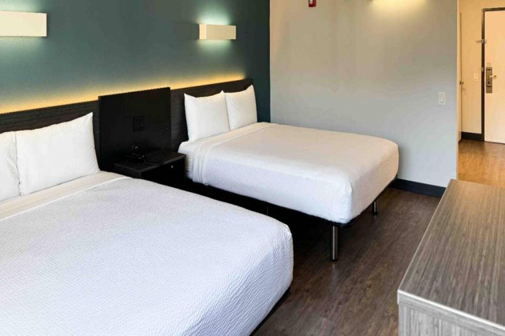 Habitació d'hotel amb dos llits individuals, una tauleta de nit, un escriptori i un armari.