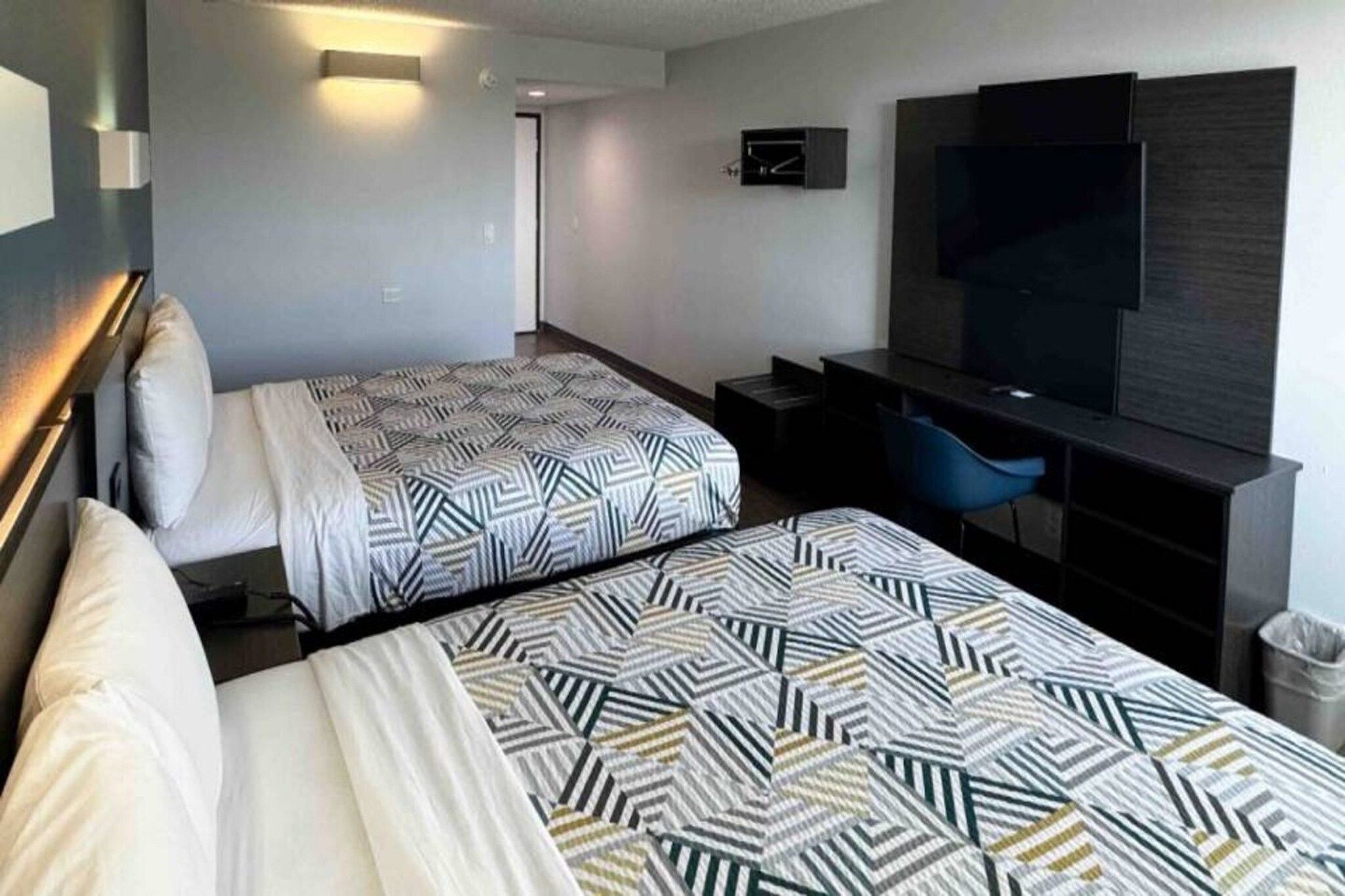 A hotel room with two beds, a TV, a desk, and a chair.