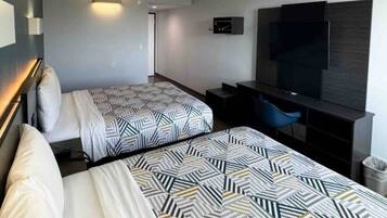 A hotel room with two beds, a TV, a desk, and a chair.