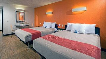 A hotel room with two beds, a small table, a chair, and a mirror.