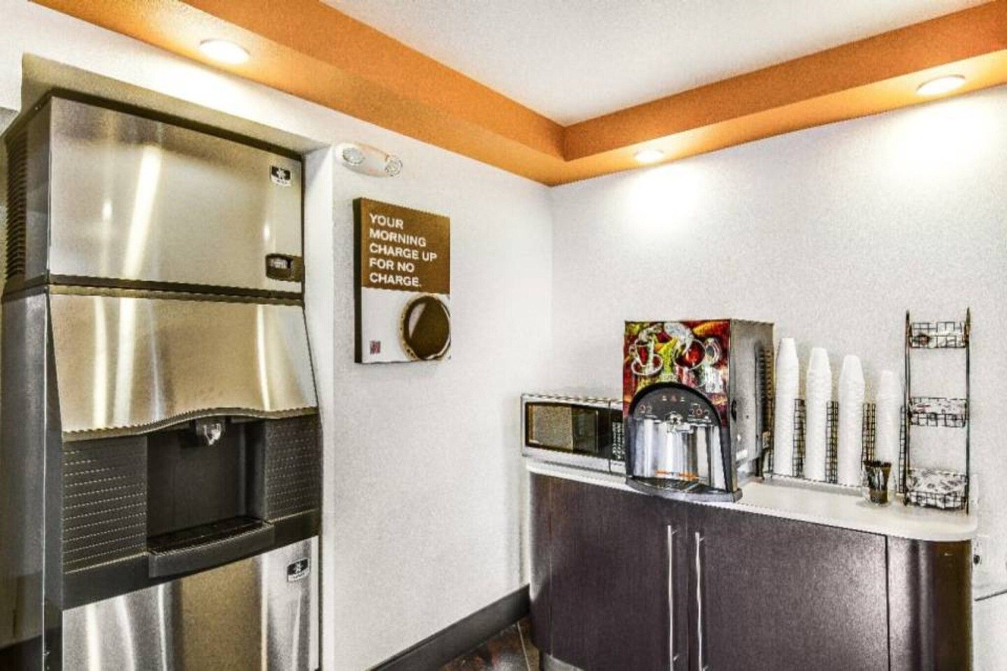 A kitchenette with a coffee machine, a microwave, and a stainless steel refrigerator.