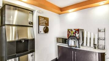 A kitchenette with a coffee machine, a microwave, and a stainless steel refrigerator.
