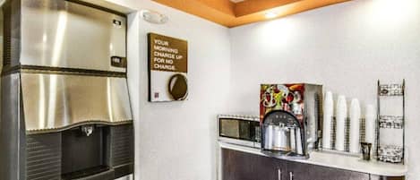 Una kitchenette equipada con cafetera, microondas y refrigerador de acero inoxidable.