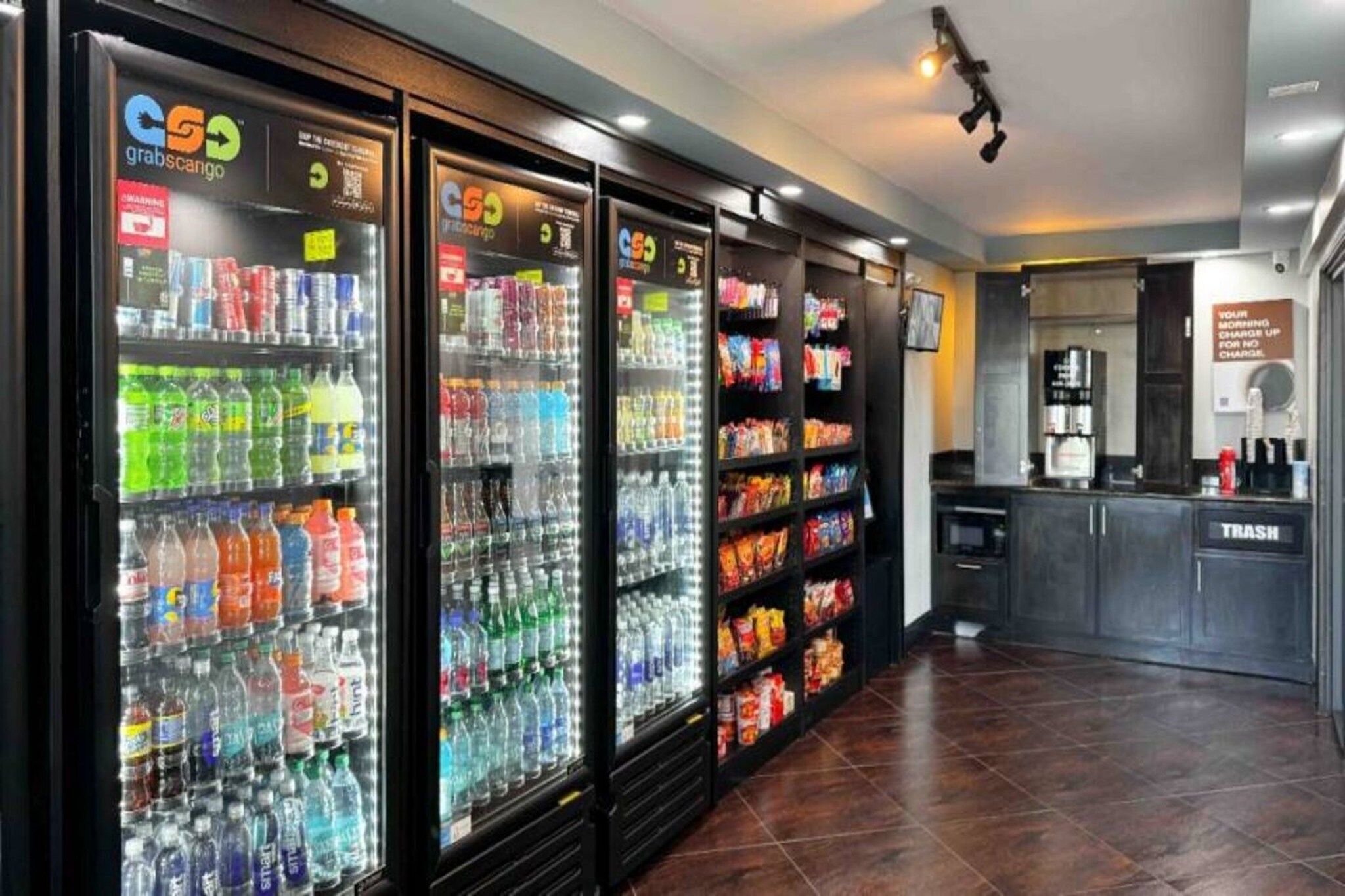 Une rangée de distributeurs de boissons et d’étagères à collations dans un espace commercial.