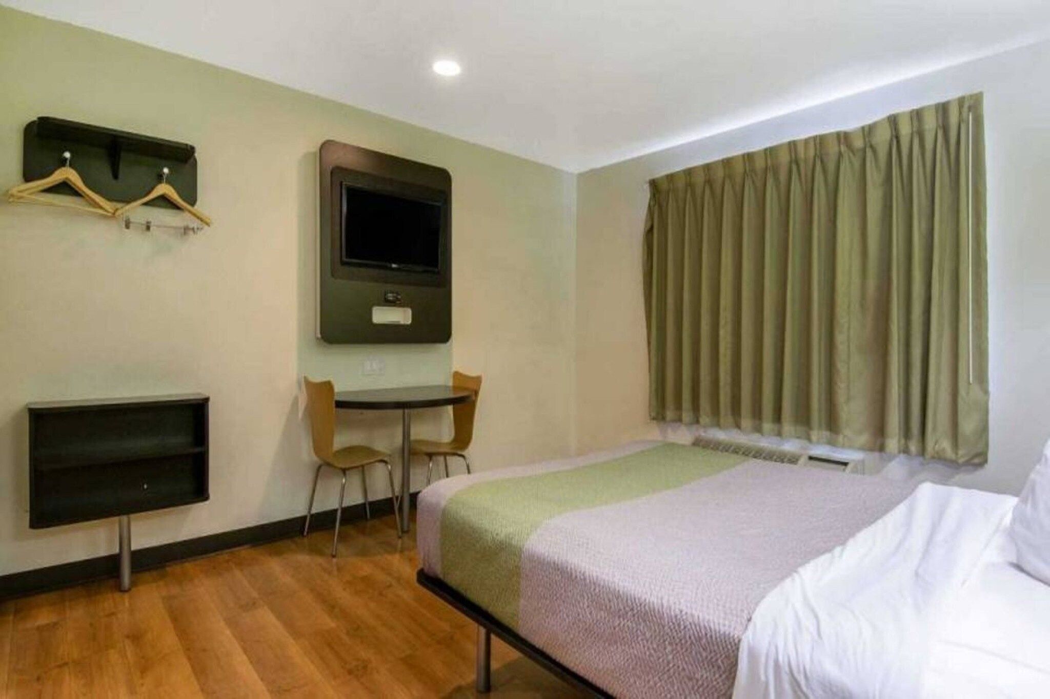 Una habitación de hotel con cama, escritorio, televisor y una silla.
