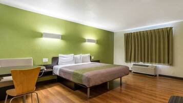 Een hotelkamer met een bed, een bureau, een stoel en een raam met gordijnen.