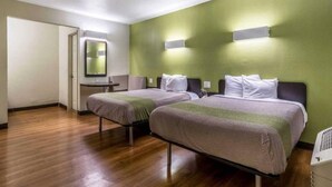 Een hotelkamer met twee bedden, een tafeltje en een spiegel.