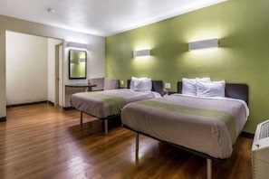 Habitación de hotel con dos camas, una mesita y un espejo.