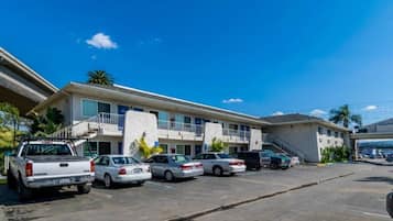 Un motel con estacionamiento, una pasarela techada y un edificio con múltiples ventanas y balcones.