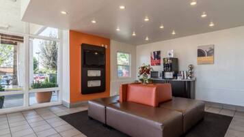 A modern waiting area with a sofa, a television, and a coffee machine.